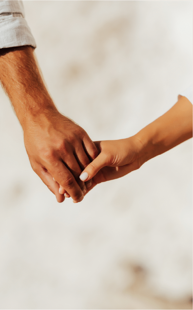 Mãos de um homem e uma mulher se tocando suavemente, simbolizando carinho e apoio.