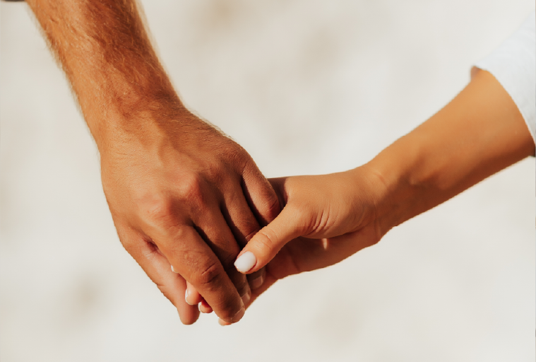Mãos de um homem e uma mulher se tocando suavemente, simbolizando carinho e apoio.